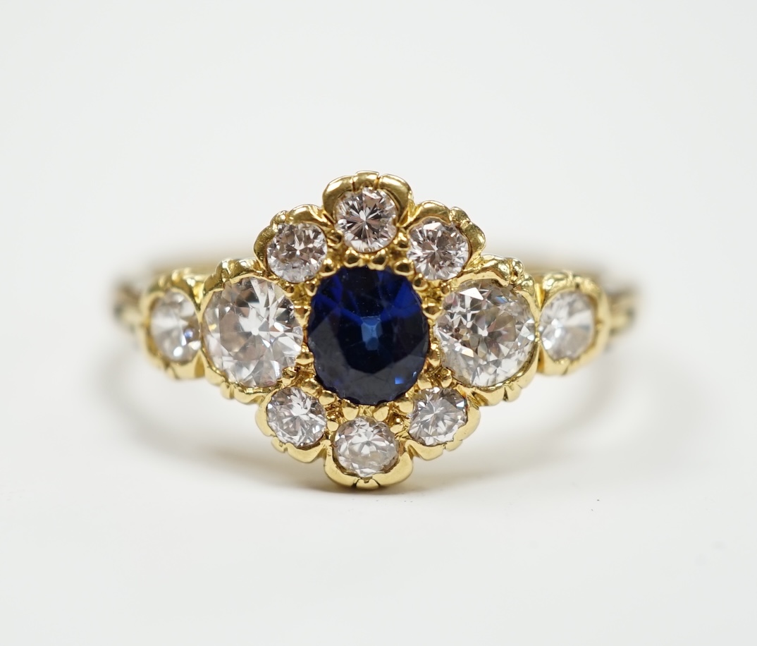 A modern yellow metal, synthetic sapphire and diamond set flower head cluster ring, with hinged shank, size U, gross weight 5.1 grams.